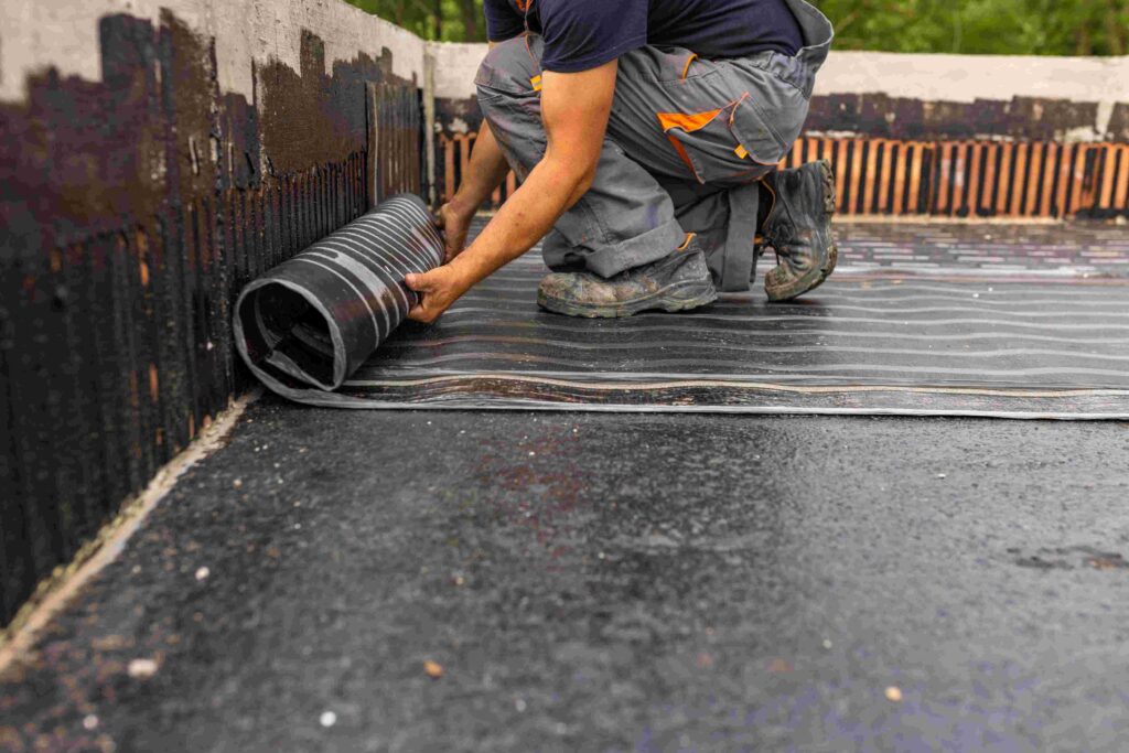 Worker laying the vapor barrier for the roof, bituminous membrane to be welded with flame